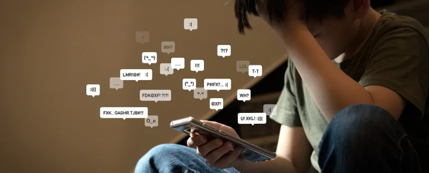 A child is looking at a smart phone with various chat bubbles with frown-faces.