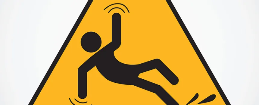 A triangular yellow sign shows a stick figure slipping on a wet surface.