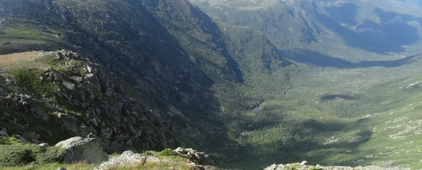 A large green valley is shown from atop a mountain on the Jewell Trail in the Presidential Range of the White Mountains.