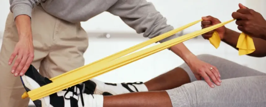 A physical therapist is helping someone use resistance bands.