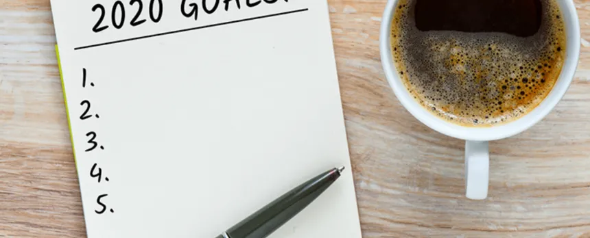 A coffee sits next to a checklist of 2020 goals.