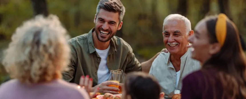A group of adults are sitting around a picnic.