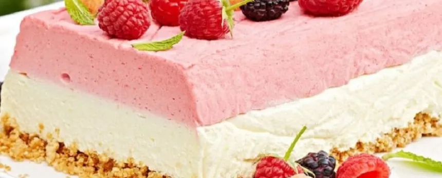 Berries are on top of and around a pink and white icebox cake.